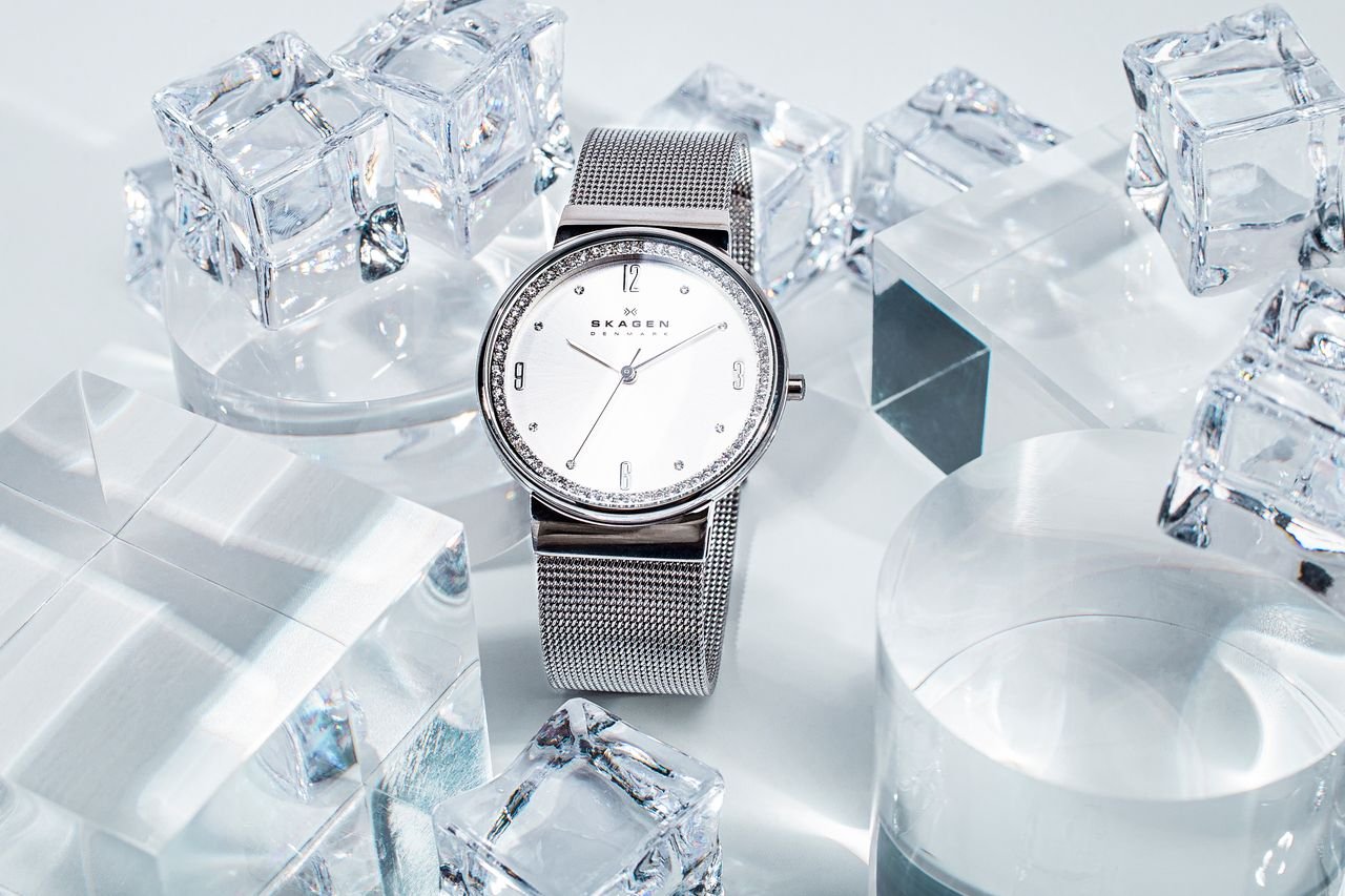 Elegant silver watch surrounded by artistic ice cubes on a sleek surface.