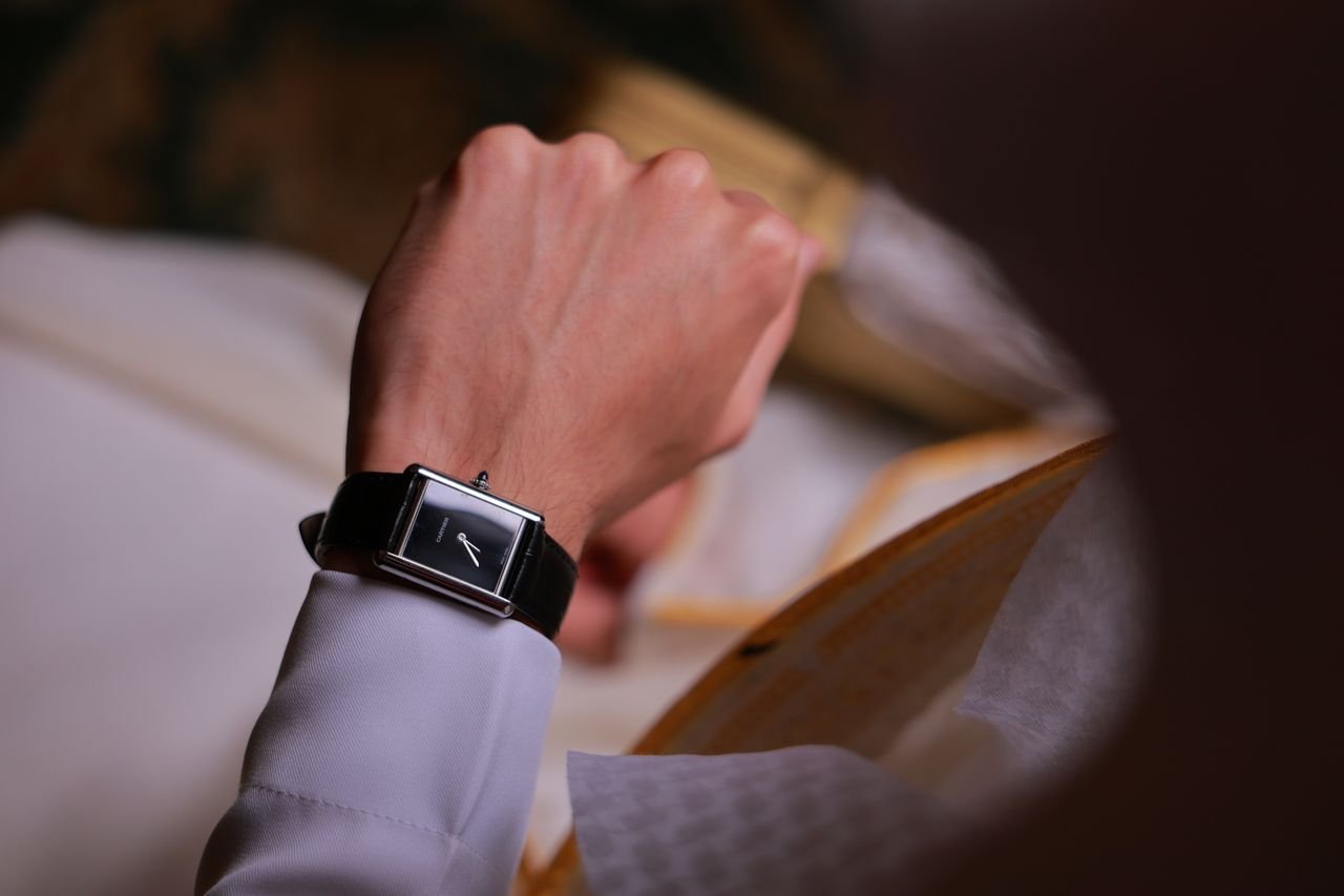 Elegant wristwatch on wrist of person engaged in reading a book indoors.